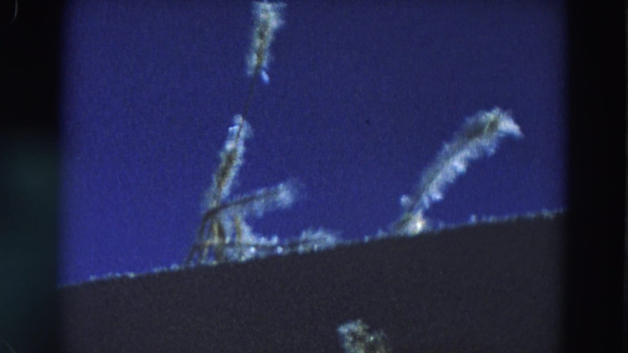 Several pale wisps appear over a dark sloping foreground against blue night sky.