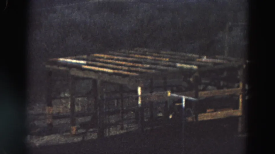 1968 Diller, Nebraska 8mm frame showing the outdoor industrial-looking structure from a similar angle in dim light.