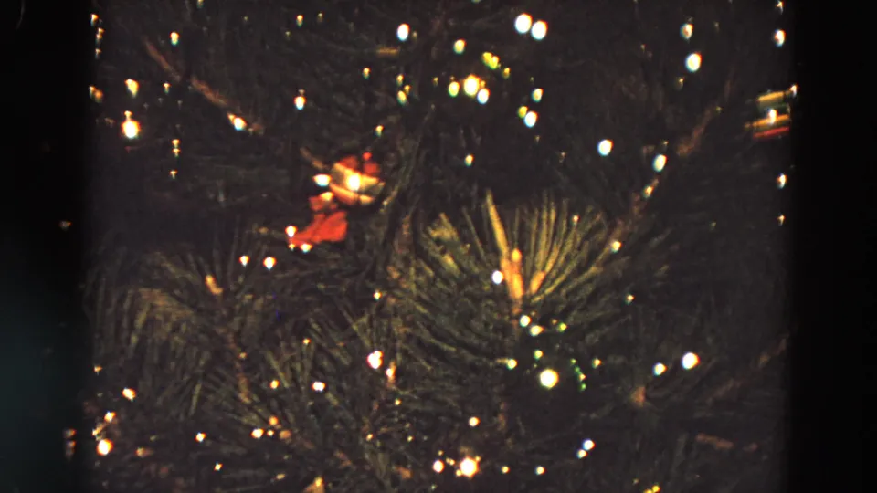 1968 Diller, Nebraska 8mm frame showing glowing Christmas tree lights and ornaments against a dim interior.