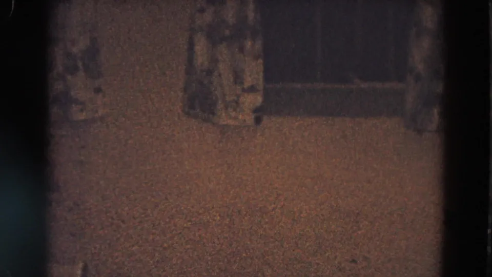 Diller, Nebraska home-movie frame with curtains, carpet, and the top edge of a lit Christmas tree visible in low light.