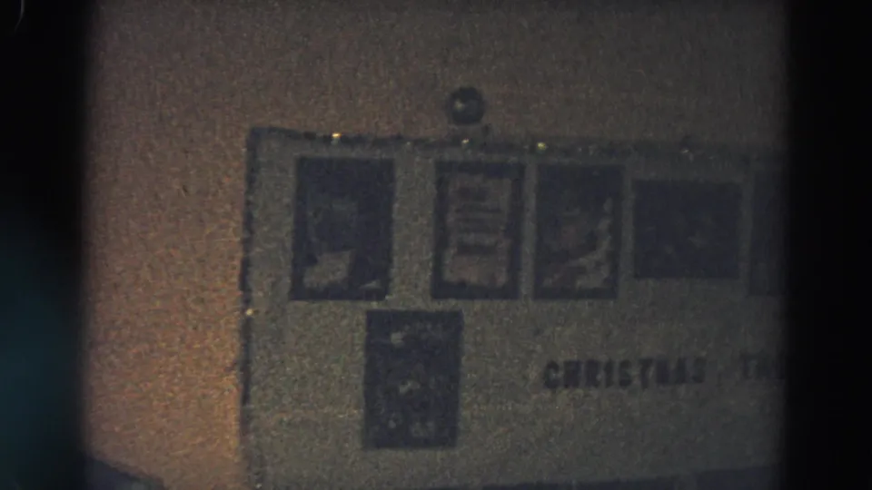 Dim 8mm frame from Diller, Nebraska, showing a holiday wall display with small panels and partially visible CHRISTMAS text.