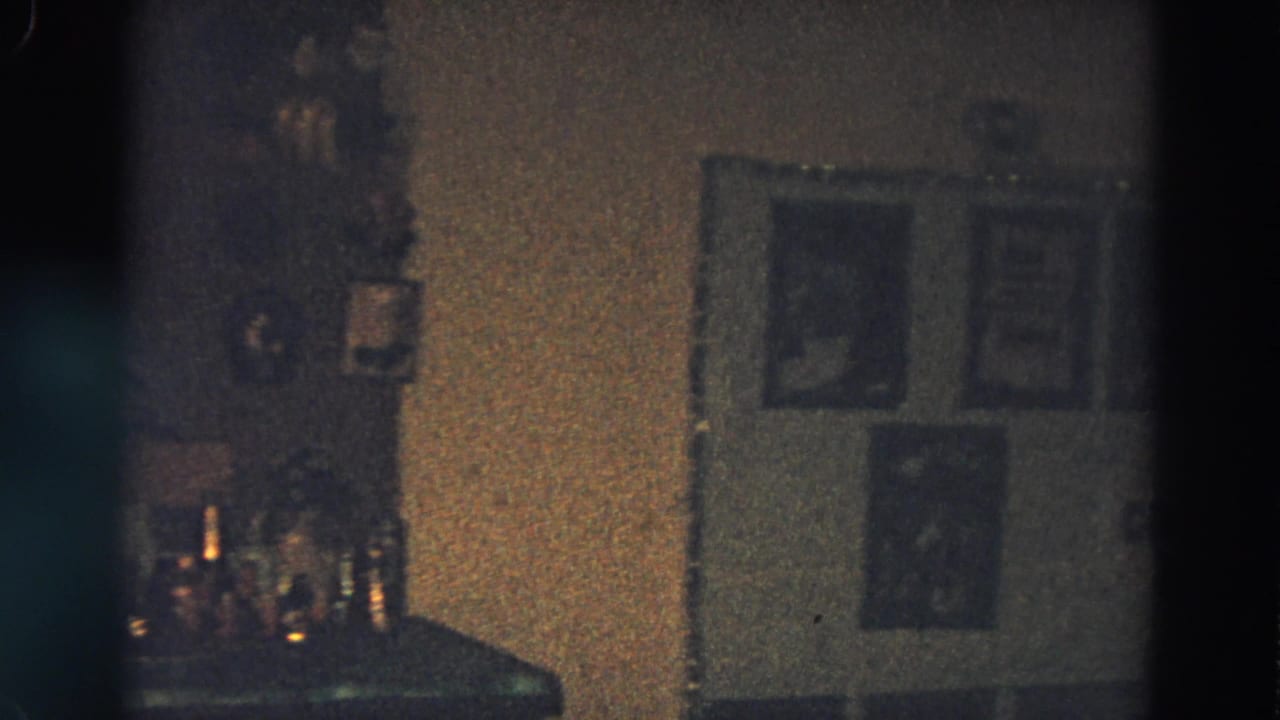 Dim interior counter with bottles and framed pictures on the wall.
