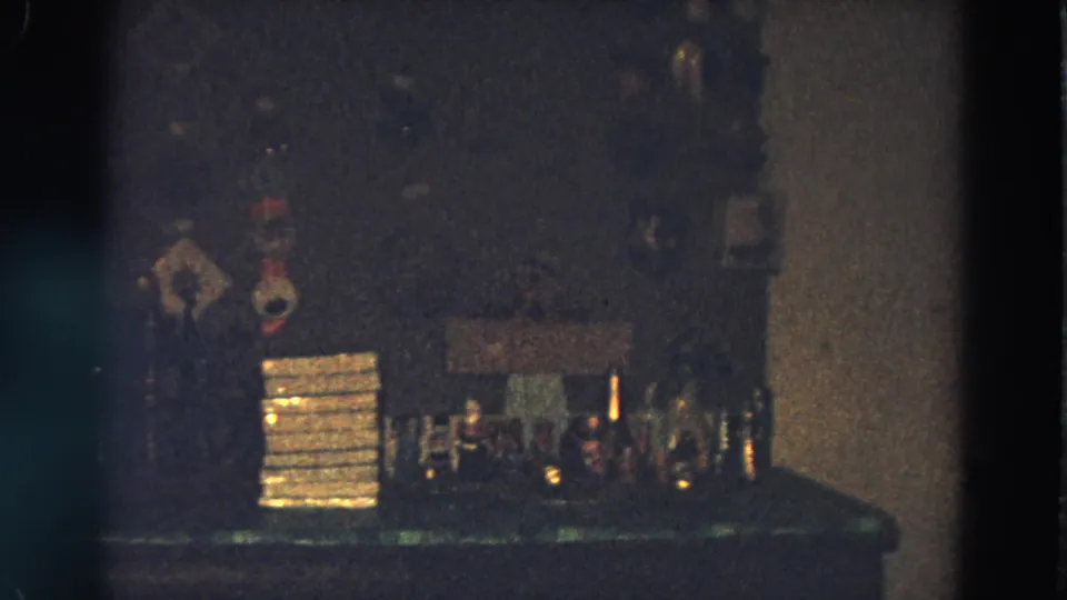 Dim 1968 Diller, Nebraska party frame with a makeshift bar, bottles, glasses, stacked items, and framed wall decor.