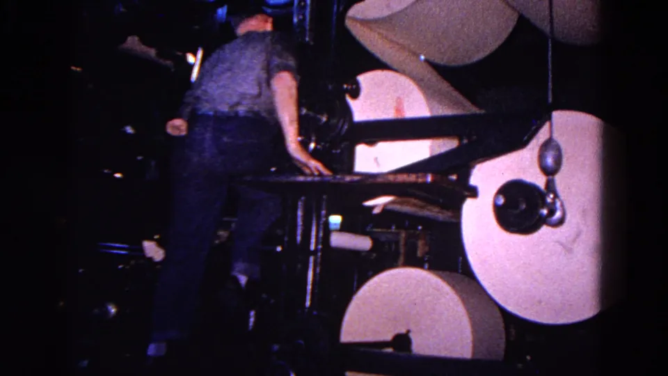 A worker in the Trenton 1967 clip stands beside a printing press, with oversized paper rolls and metal arms filling the frame.