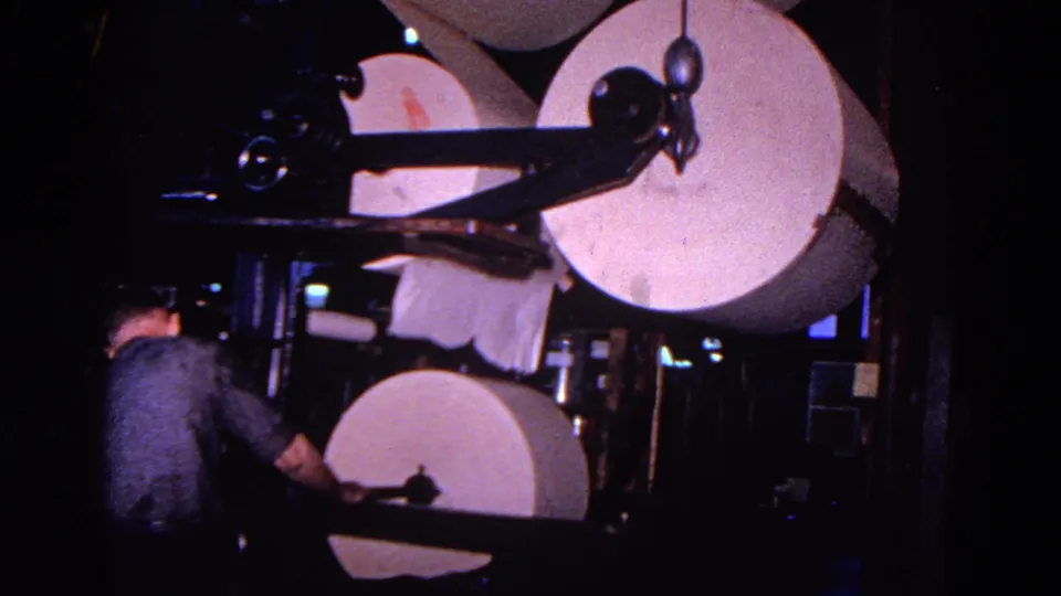 The 1967 Trenton footage shows a worker near stacked paper rolls and a heavy paper-processing machine in low light.