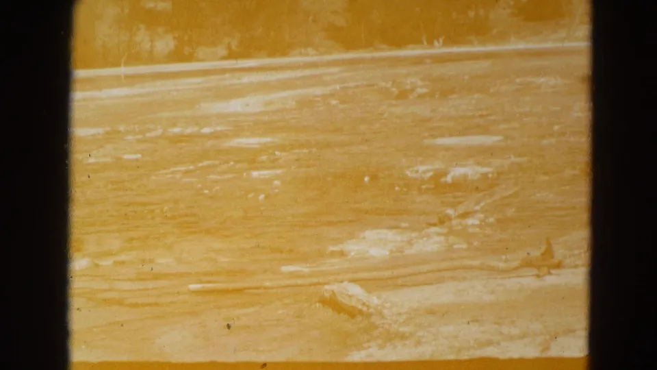 1967 Yellowstone 8mm frame showing a yellow, overexposed view of flooded mineral ground with pale deposits and visible film gate edges.