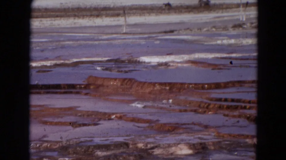 1967 Yellowstone 8mm frame with reddish mineral terraces, pale flats, shallow water, and visible contact-sheet frame divisions.