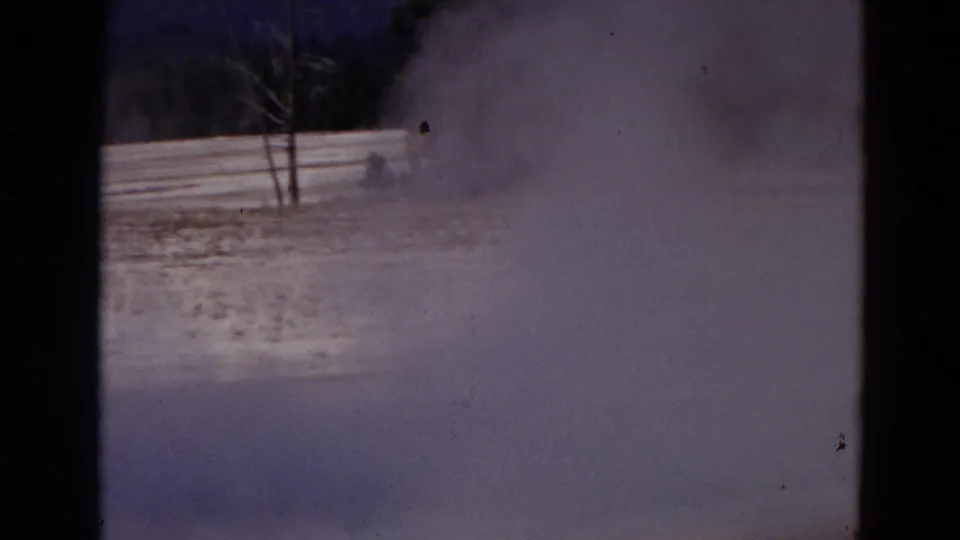 1967 8mm Yellowstone view of steam rising near small trees at the Old Faithful geothermal area.