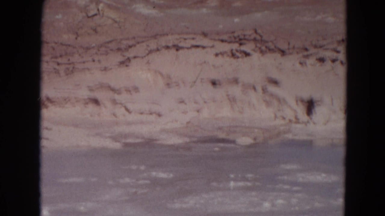Pale mineral bank above gray-blue steaming water with dark 8mm frame edges.