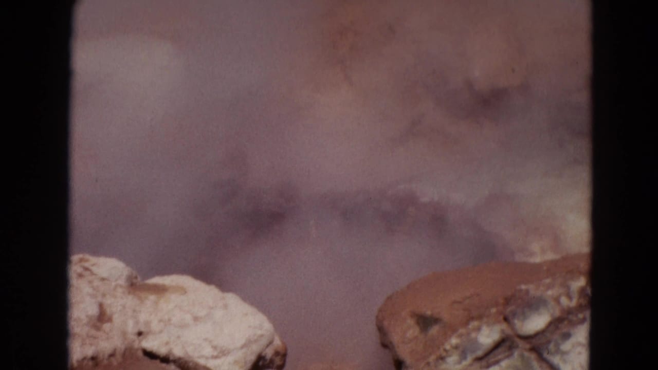 1967 Yellowstone 8mm frame with drifting steam, pale rocks, and muddy geothermal water churning at the edge of view.