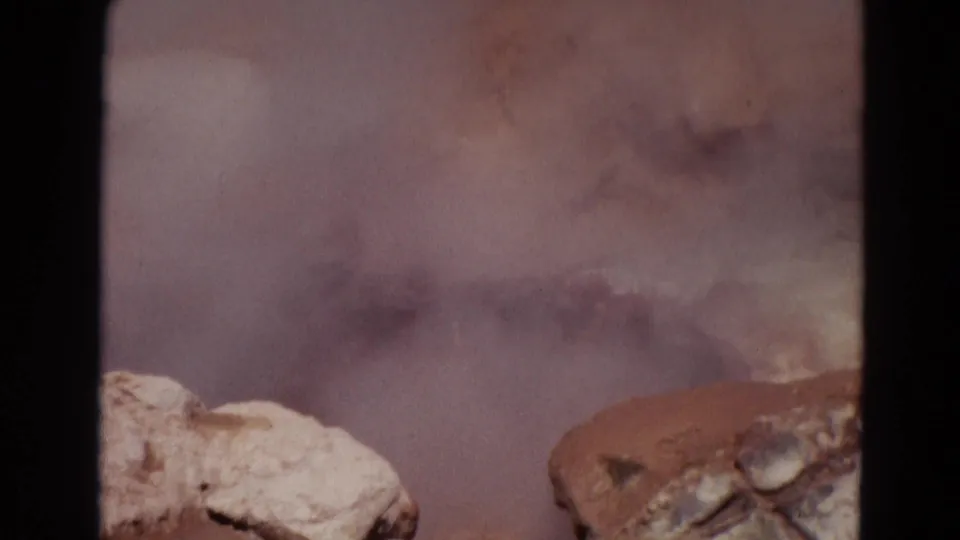 1967 Yellowstone 8mm frame with drifting steam, pale rocks, and muddy geothermal water churning at the edge of view.