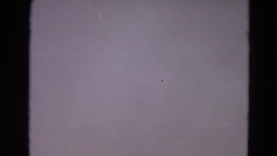 Soft, nearly blank 8mm frame from the Yellowstone home movie, with dark gate edge, grain, and faint exposure variation.