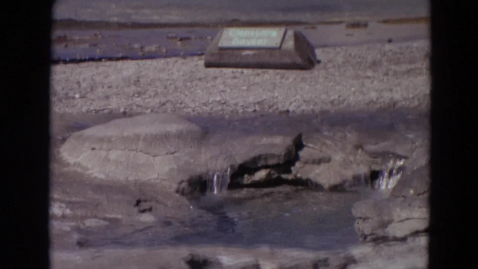 1967 Yellowstone 8mm frame showing the Clepsydra Geyser sign and a wet rocky fissure where water continues to bubble.