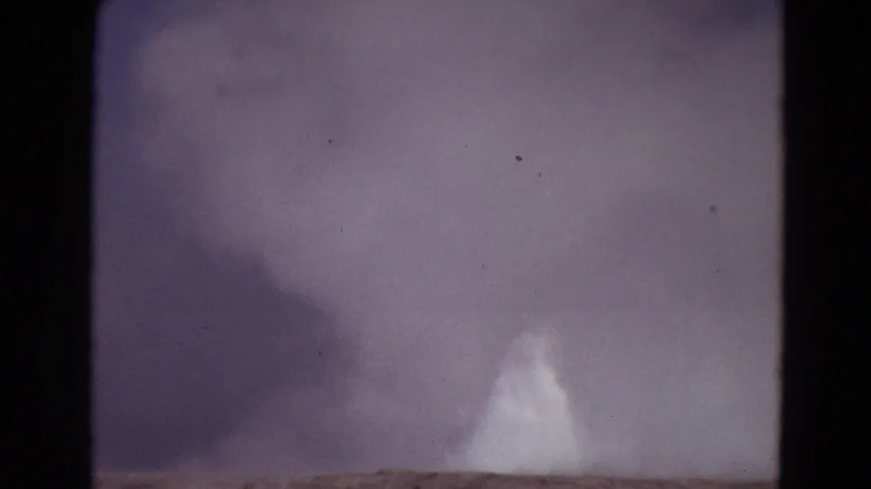 1967 Yellowstone 8mm frame showing a bright geothermal plume rising from low terrain in hazy light.