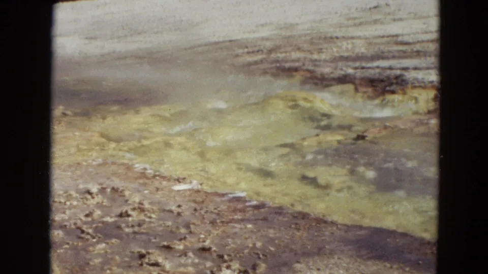 1967 Yellowstone frame showing yellow-toned mineral ground or geothermal runoff near a pale wet basin.