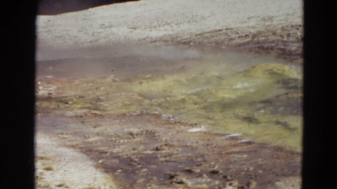 Steaming mineral ground with yellow and brown geothermal deposits.