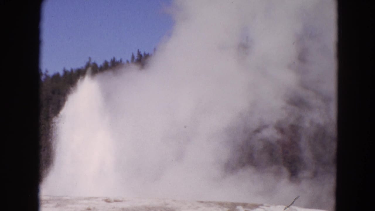Large geyser eruption partly hidden by drifting steam.