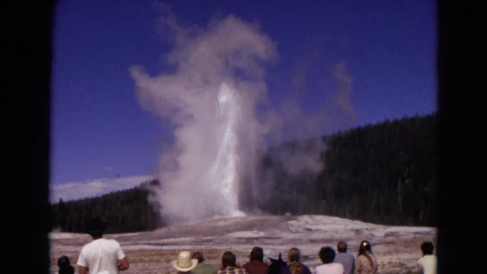 A Yellowstone tourist crowd watches Old Faithful's steam and water plume during a 1967 8mm home-movie shot.
