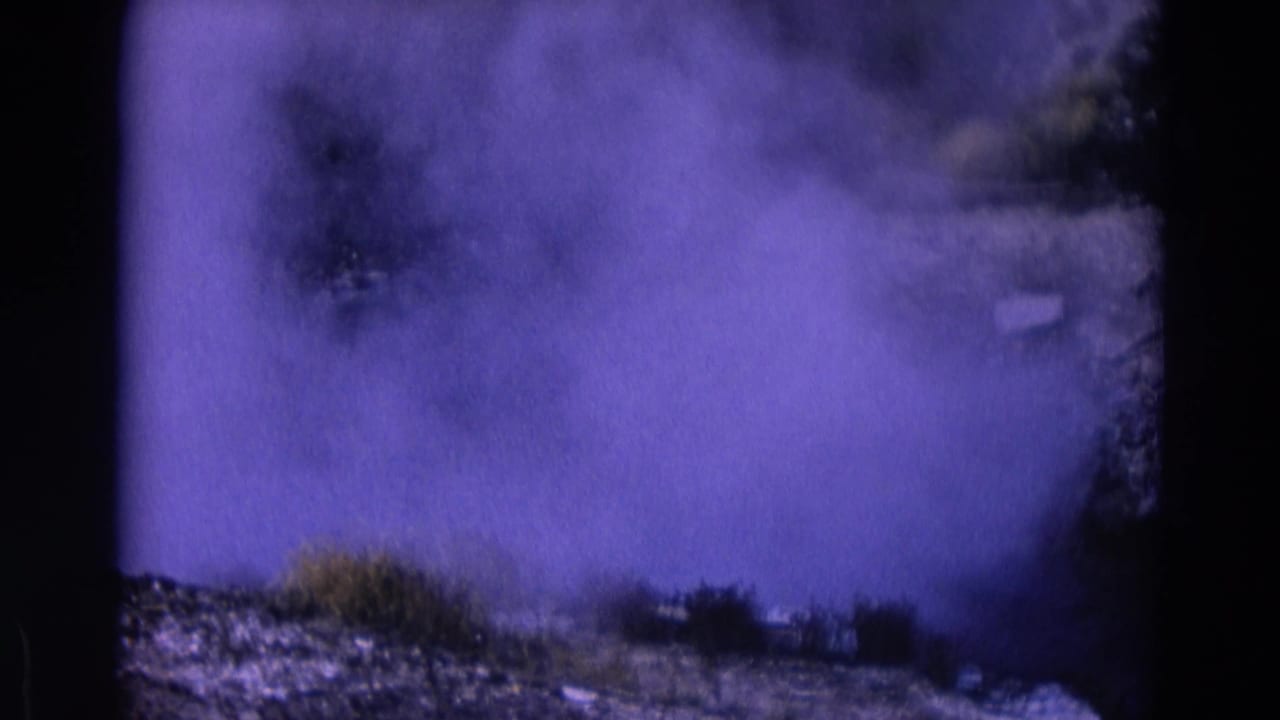 Steam billows over rocks and low brush in a color-shifted 8mm frame.