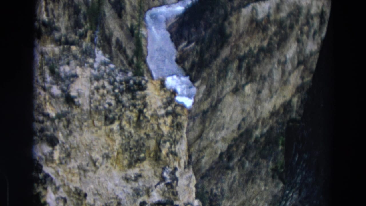 Rocky ravine with a pale icy stream winding between steep canyon walls.