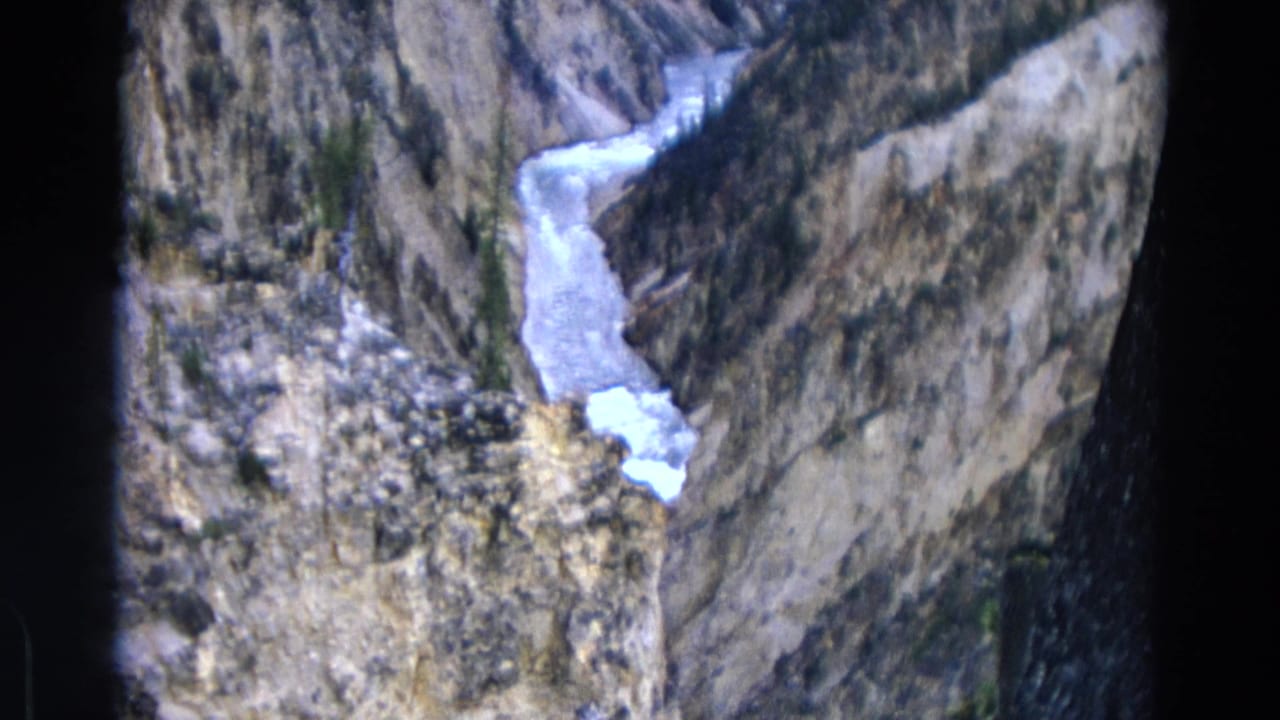 Narrow icy stream bends through a rocky mountain ravine with shadowed slopes.