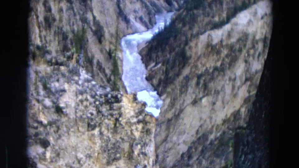 1967 Yellowstone ravine view with a pale stream curving through rocky, shadowed canyon terrain.
