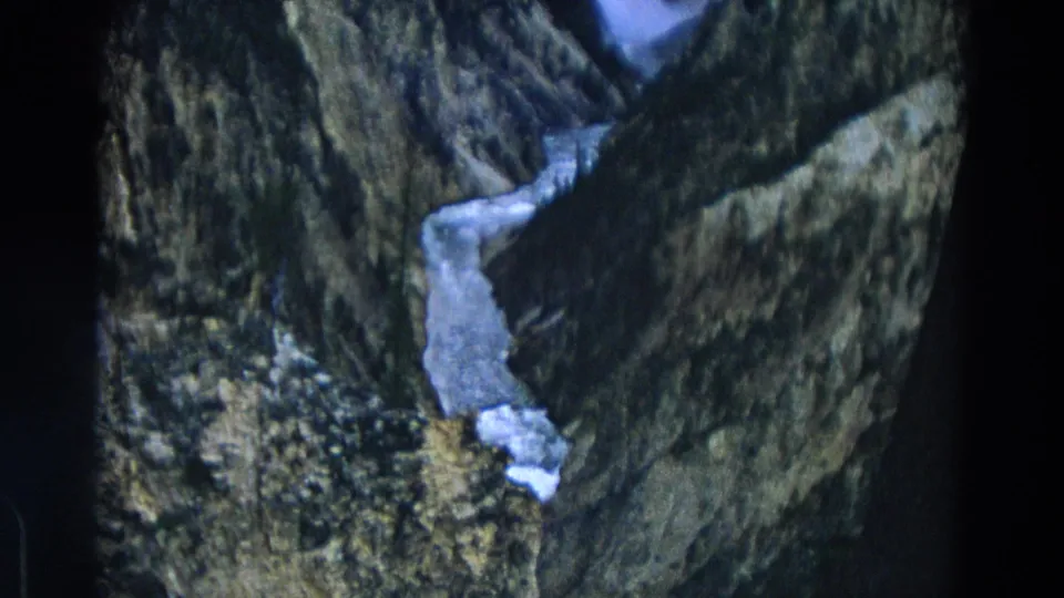 Vintage 8mm Yellowstone frame looking down on icy water running through a steep ravine.