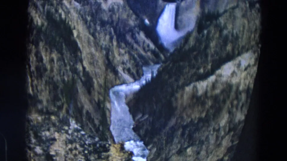 1967 Yellowstone home-movie still of white icy water threading through a dark rocky ravine.