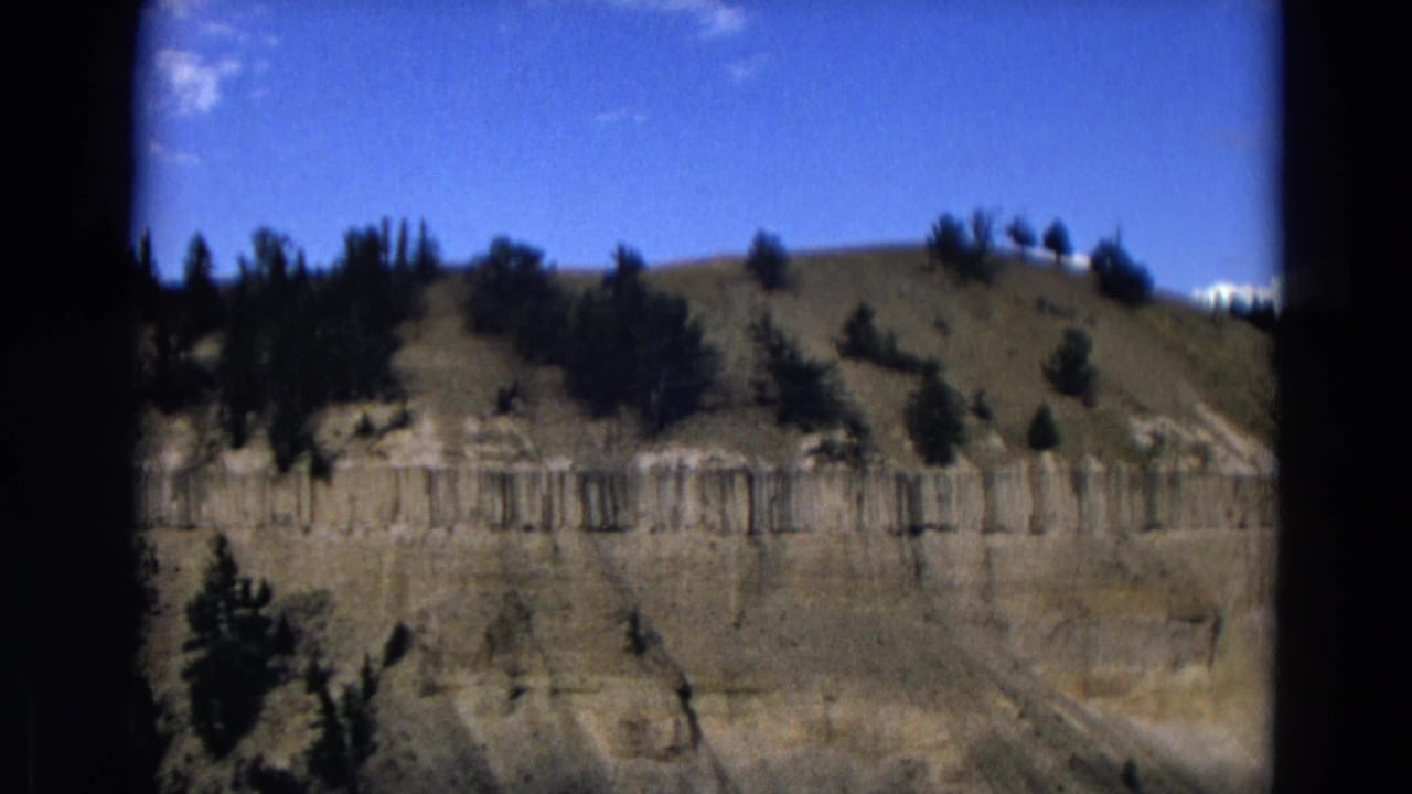 Rugged cliff strata with evergreens along the upper slope.