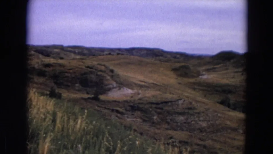 1967 Yellowstone home-movie landscape view showing rolling grassy hills, low ridges, and a pale overcast sky.