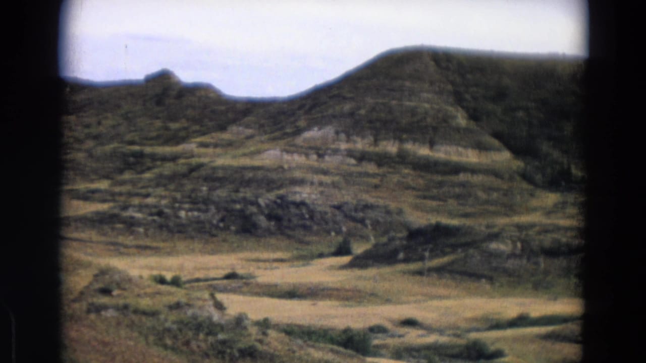 Wide landscape with layered hills, scrub vegetation, and open valley floor.