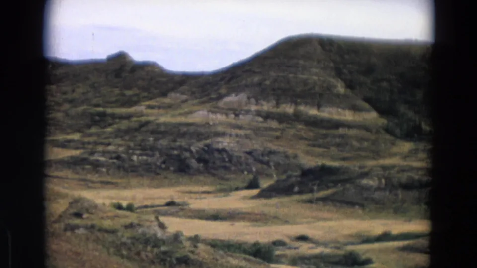 Wide 8mm view of Yellowstone Park metadata terrain, with arid hillsides, a valley floor, and sparse scrub under pale sky.