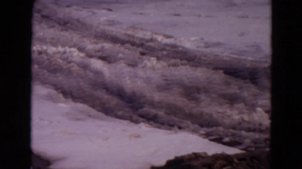 Home-movie frame of slushy lake ice and snow-covered shoreline in the Wyoming winter setting.