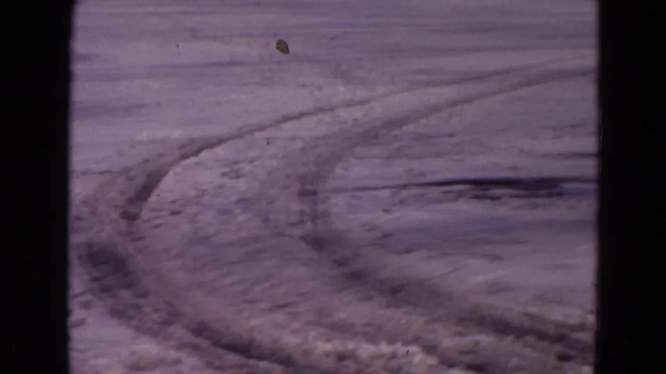 Faded 1967 Yellowstone 8mm frame of tire grooves crossing a sparse snow-dusted landscape.