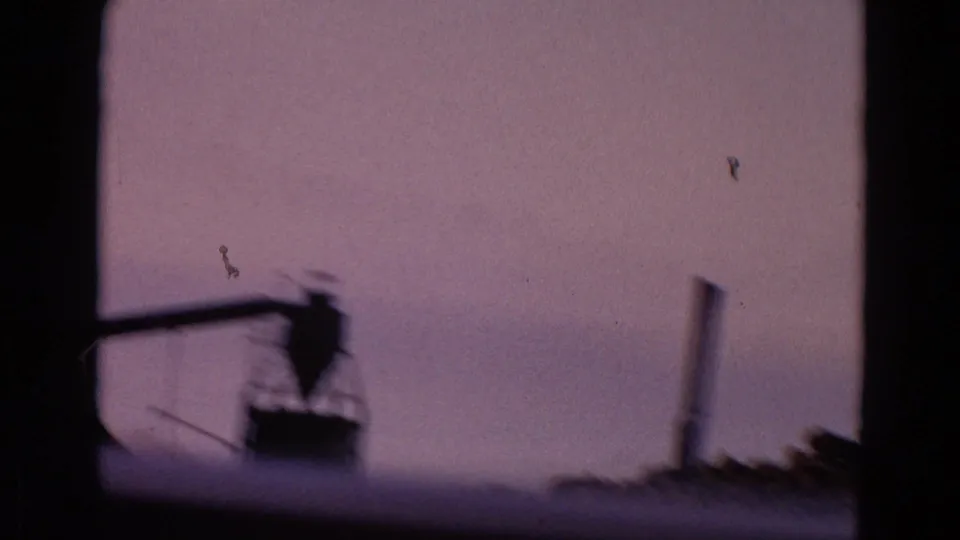 1967 8mm travel footage shows a distant industrial shape through a dark window frame near Yellowstone Park, Wyoming.