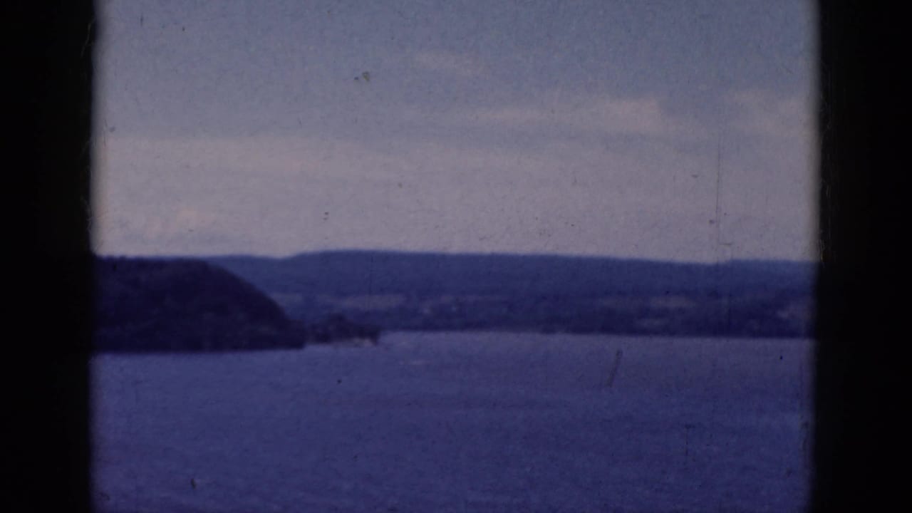 Lake and distant hills seen through dark vertical window bars.