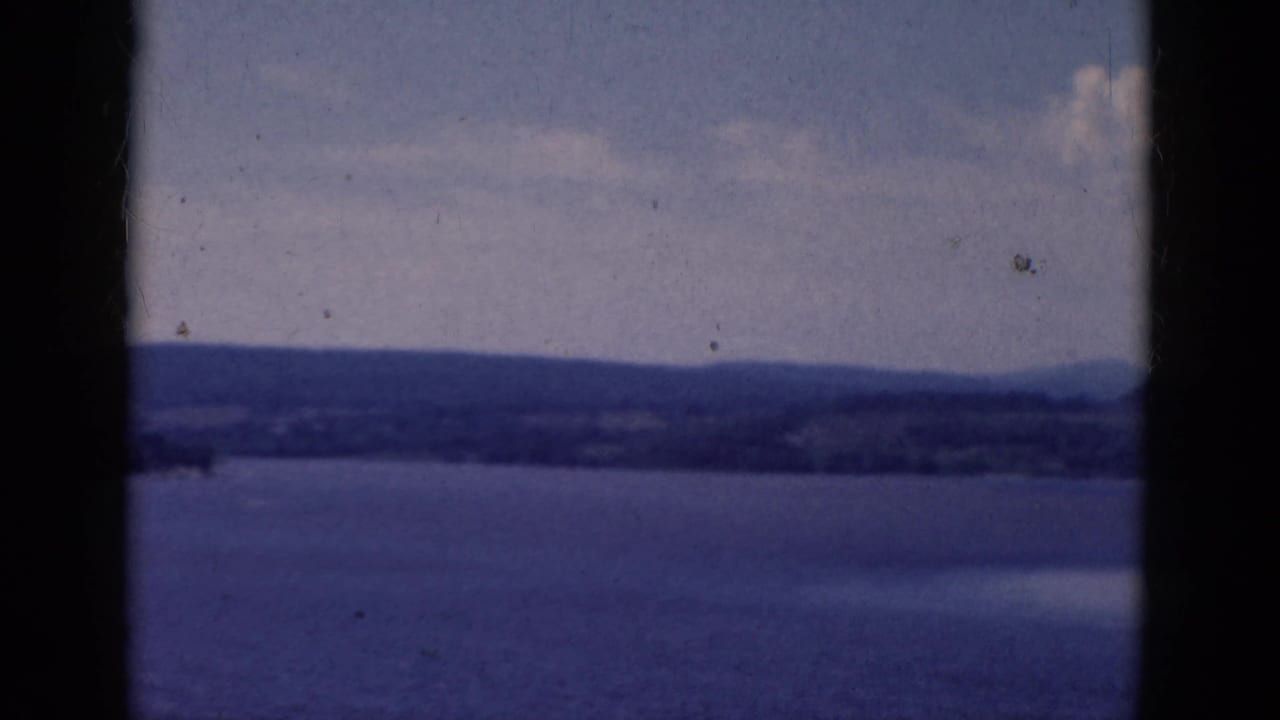 Distant lake shore and hills divided by a dark central window bar.