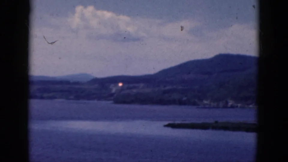 1968 8mm lake view showing a low island or shoreline at the lower right and hills beyond the water.