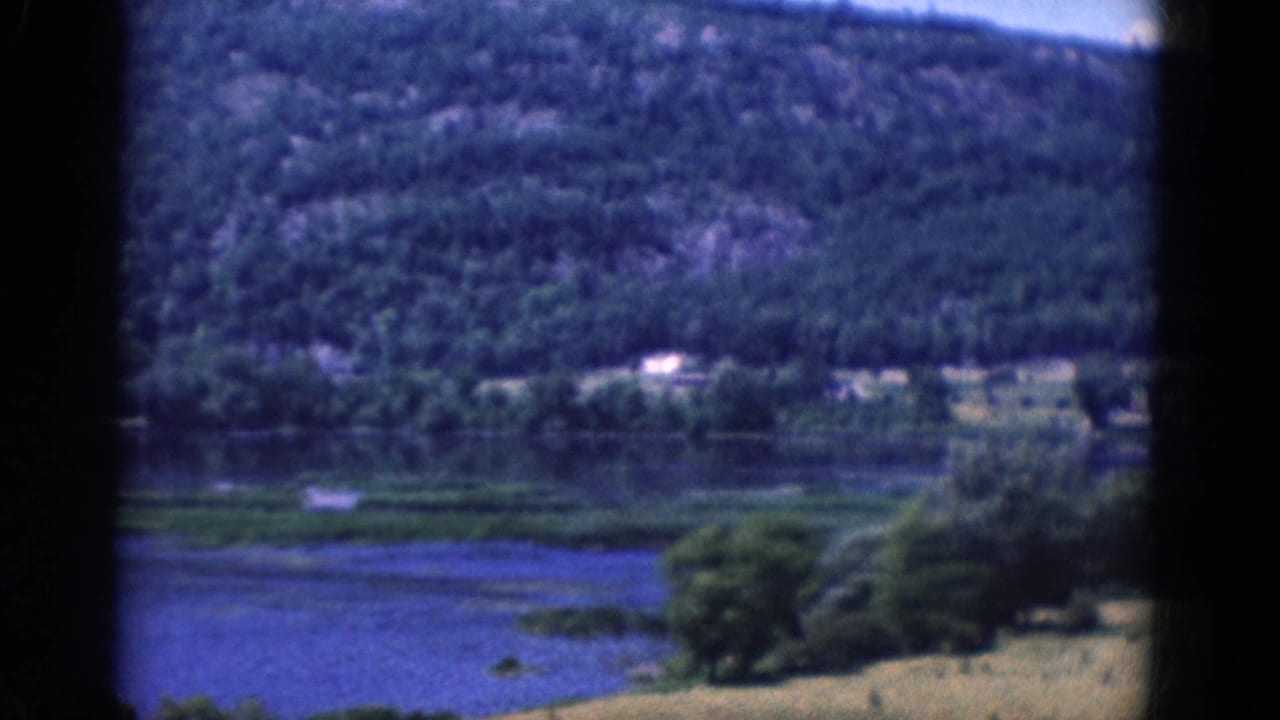 Wooded hills and water seen through dark 8mm film borders.