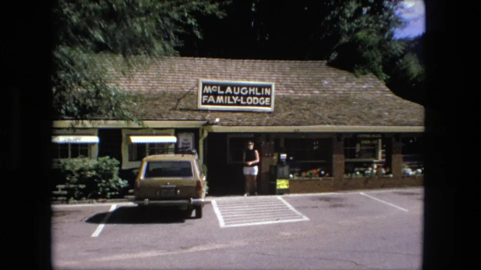 Fort Wayne motel frontage in 1976 showing the McLaughlin Family Lodge sign, station wagon, flower boxes, and woman at the entrance.