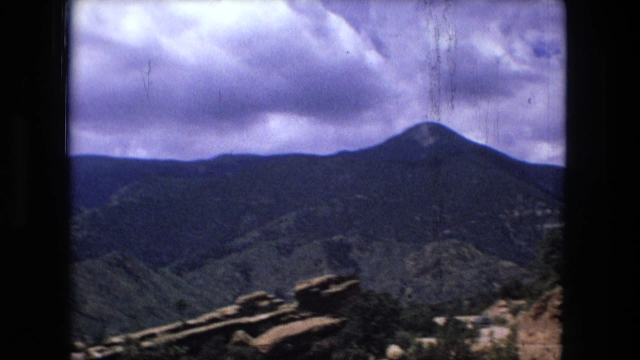 Mountain ridges under cloudy sky with rocky ledges in the foreground.