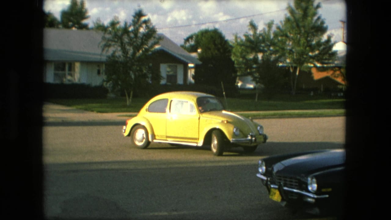 Yellow Volkswagen Beetle driving past ranch-style homes in Fort Wayne, Indiana, in 1976 home-movie footage.