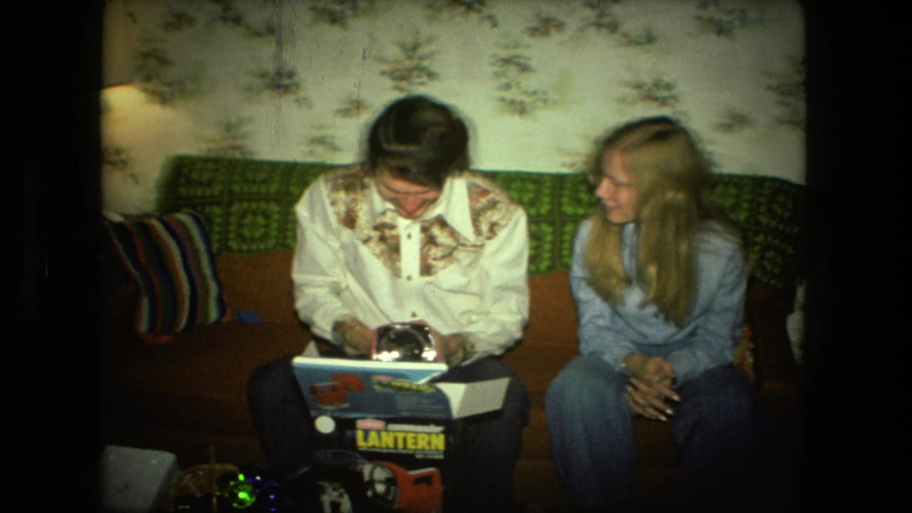 Young man opens a Coleman lantern box on a couch as a blonde woman watches.