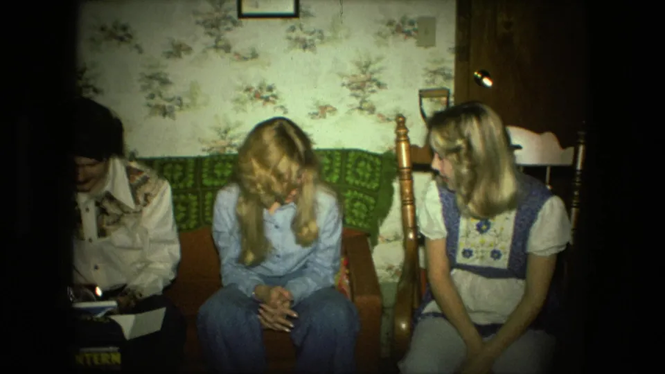 The final 1976 Fort Wayne frame shows two women seated in the living room, with the lantern box and young man partly cropped at left.
