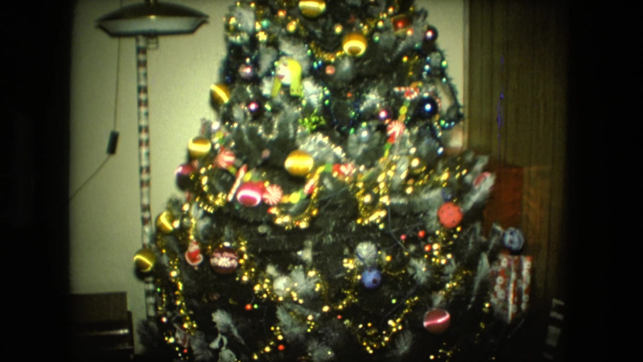 Decorated Christmas tree with ornaments, tinsel, lights, and wrapped gifts in a living room.