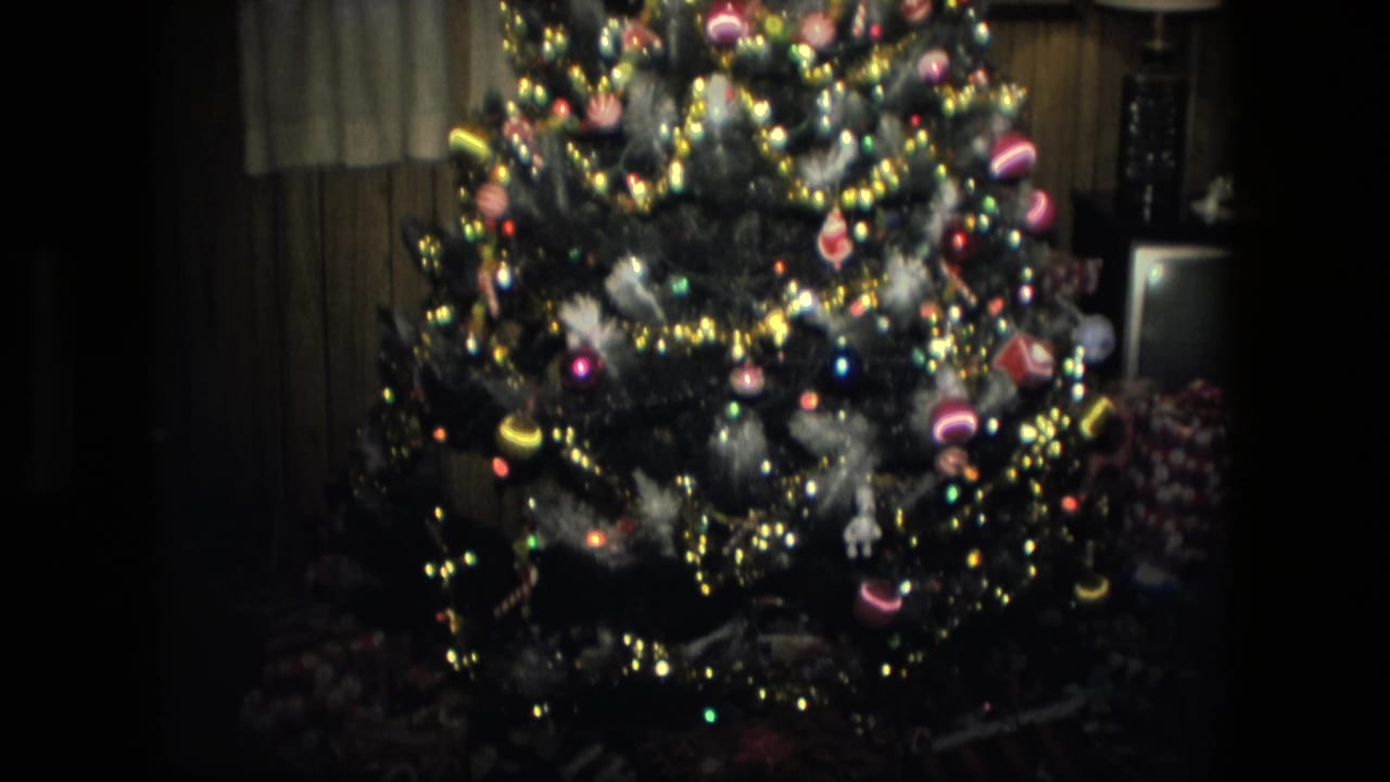 1976 Fort Wayne interior with a lit Christmas tree, shiny ornaments, tinsel, and wrapped gifts near the base.