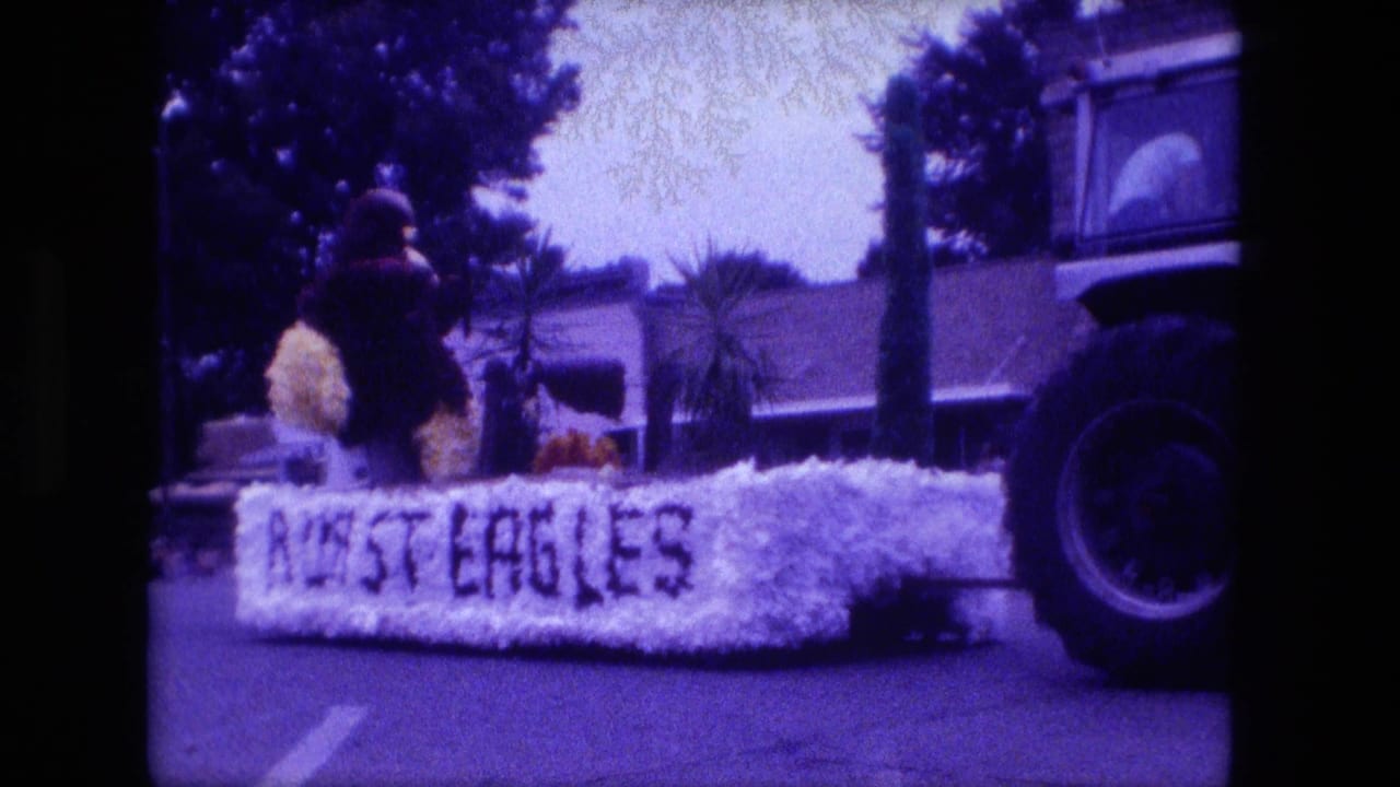 Decorated parade float with large lettering being pulled past the camera.