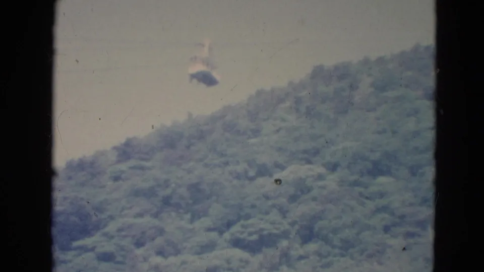 A small cable car is visible above a forested hillside in a soft, grainy 1976 Minnesota 8mm frame.