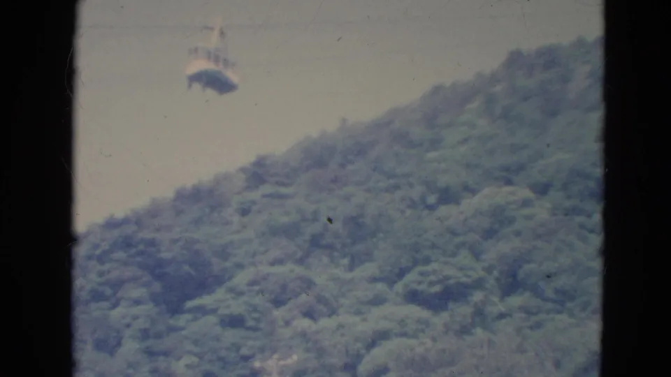 Final 1976 Minnesota frame with the gondola still suspended above the forested hill, partly bordered by a dark vertical edge.
