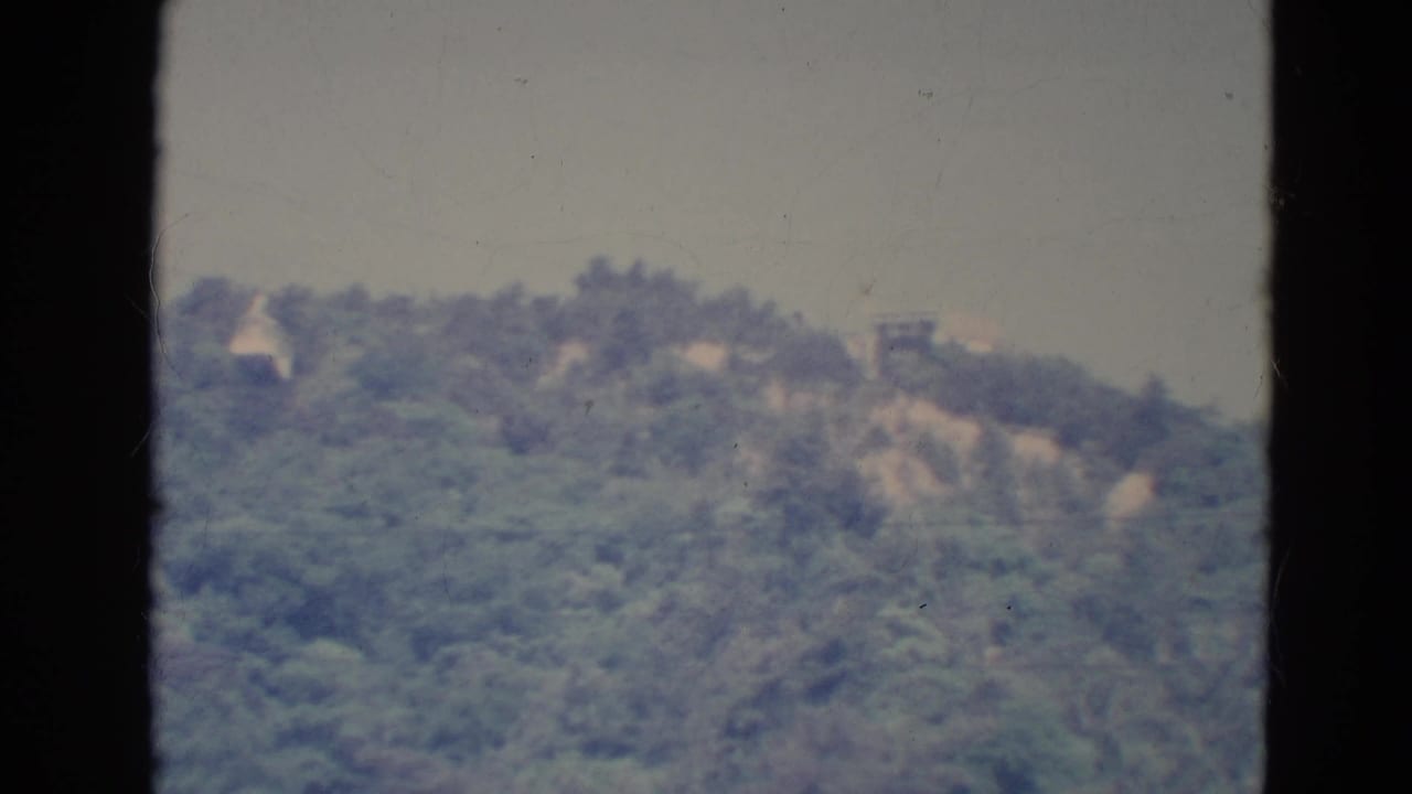 1976 Minnesota 8mm frame showing a soft, distant wooded hillside viewed through a dark window frame.